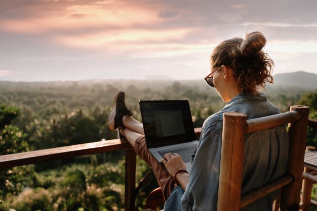 woman on laptop on balcony with beautiful view